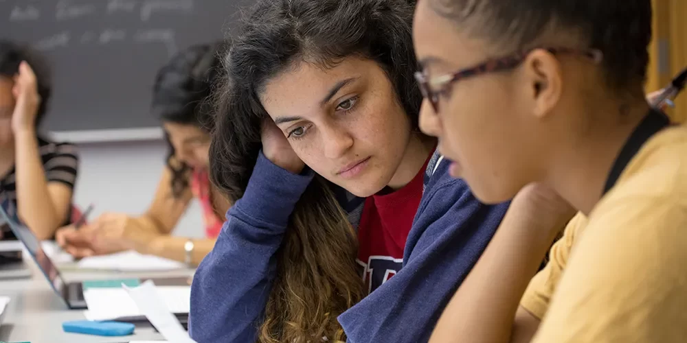 Two students studying together and reviewing papers in a classroom setting at Penn.