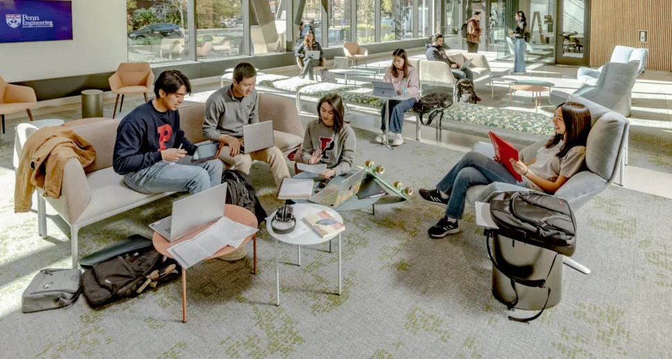 Students collaborating on laptops in an open lounge at Amy Gutmann Hall in Penn Engineering.
