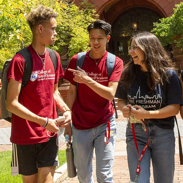 University of Pennsylvania students sharing a laugh in front of the iconic red-brick Fisher Fine Arts Library.