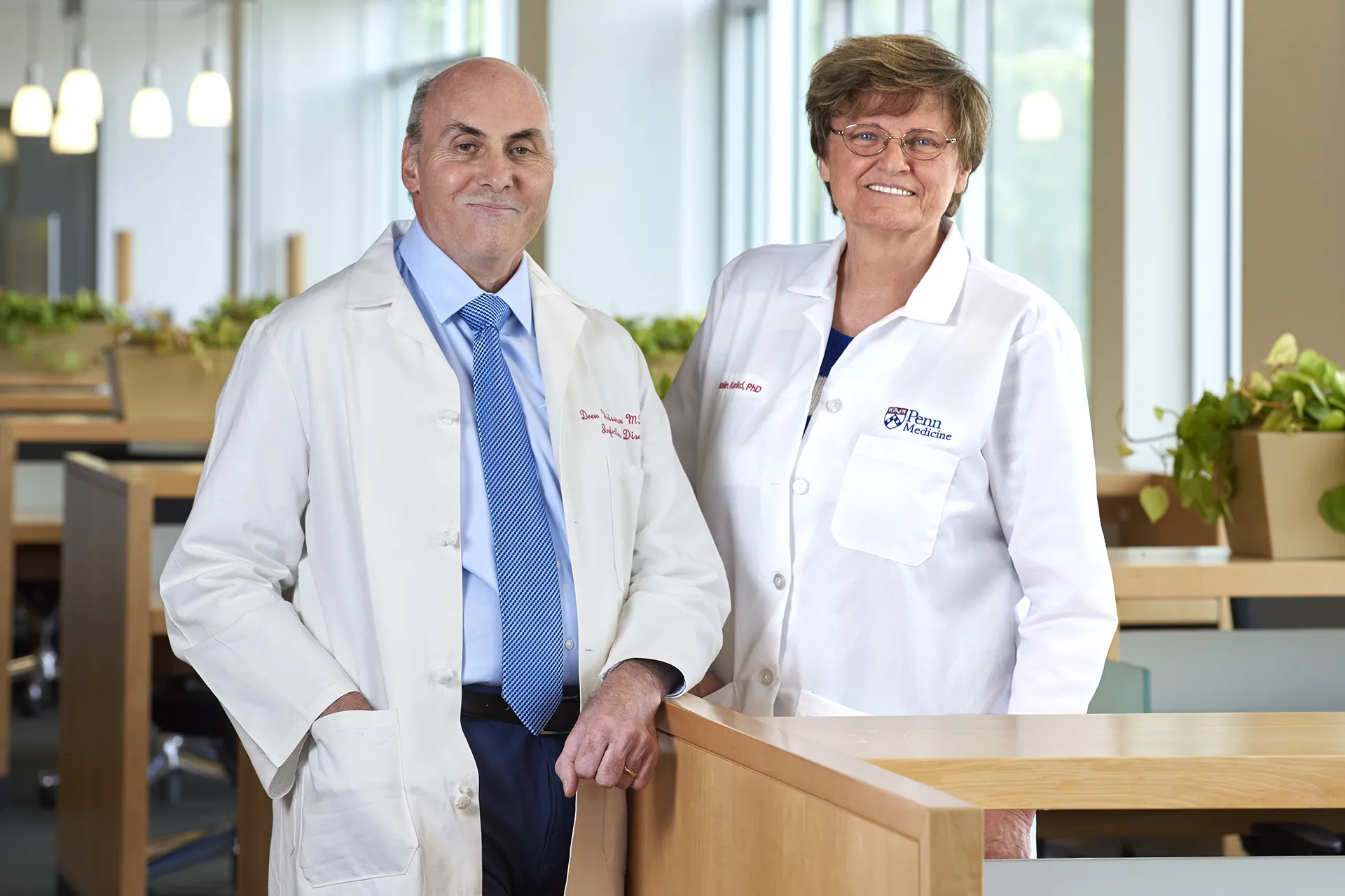 Katalin Karikó and Drew Weissman, recipients of the 2023 Nobel Prize in Medicine, wearing lab coats in a Penn Medicine research facility.