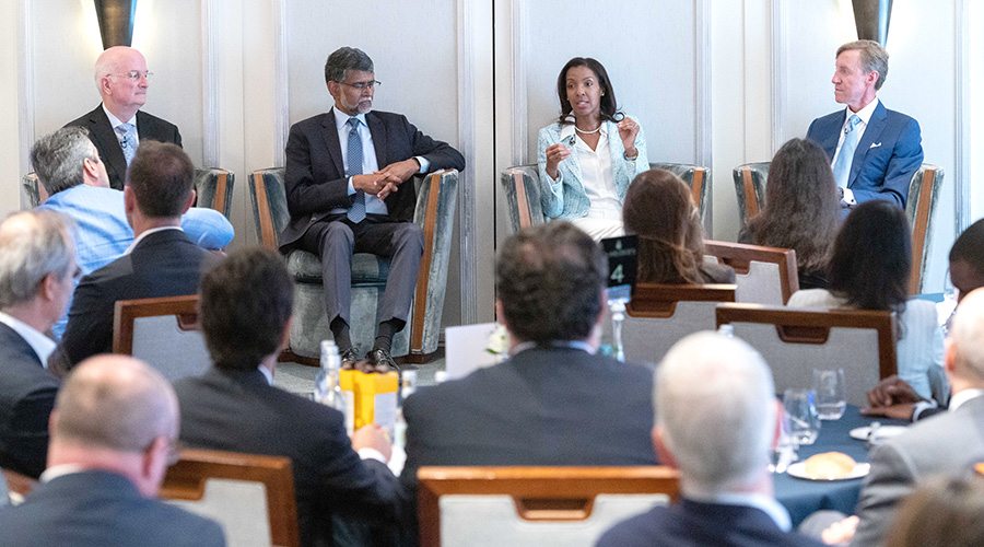 Penn leaders, including Kevin Mahoney, CEO of the University of Pennsylvania Health System; Vijay Kumar, the Nemirovsky Family Dean of Penn Engineering; Erika James, Dean and Reliance Professor of Management and Private Enterprise at Wharton; and J. Larry Jameson, Interim President of the University of Pennsylvania, sit in a row on stage as Dean James speaks to the audience.