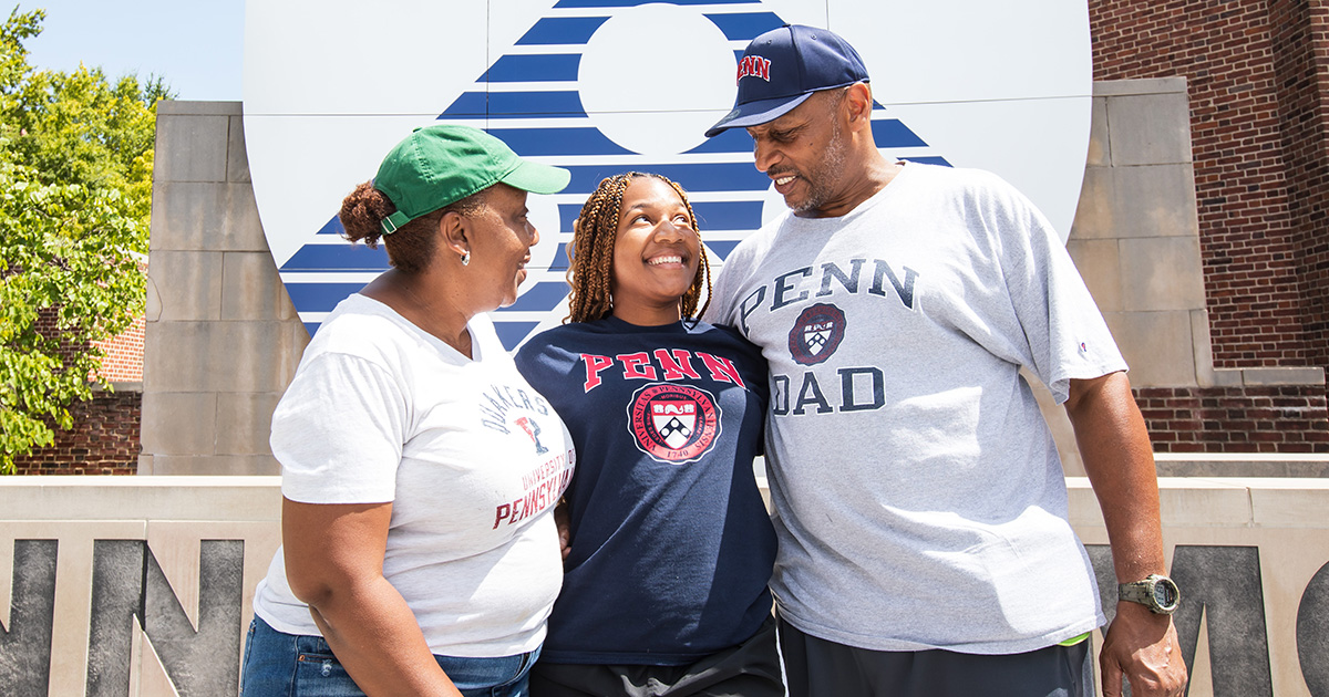 A student stands with family members on Penn Commons