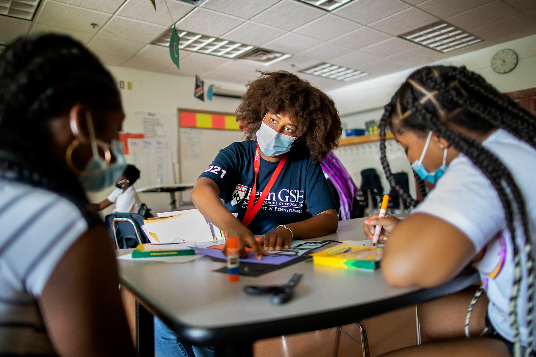 An educator affiliated with the University of Pennsylvania's Graduate School of Education works with two elementary school students in a classroom.