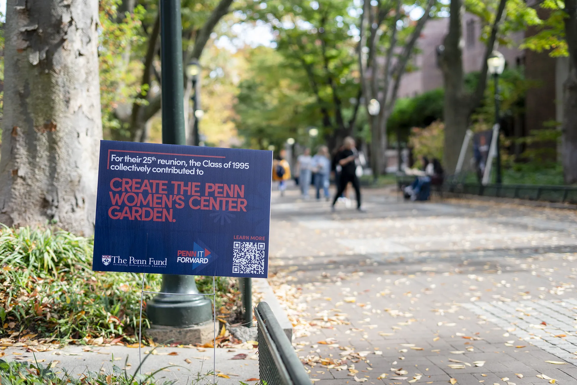 Penn It Forward sign on Locust Walk highlights the Class of 1995 gift to create the Penn Women’s Center Garden.