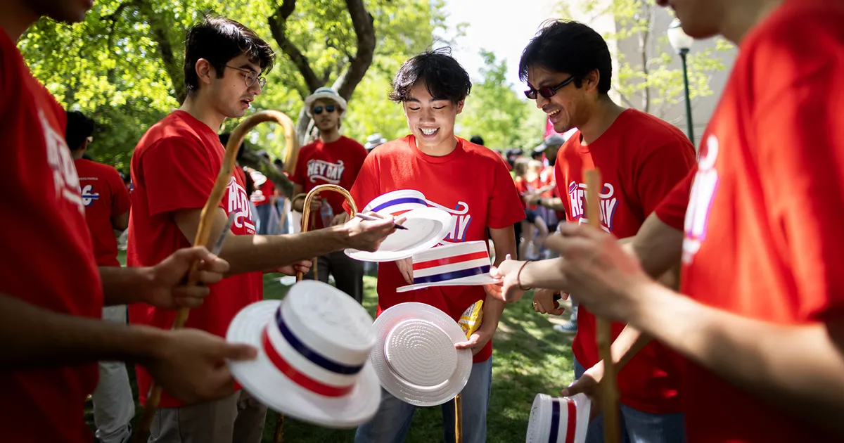 A group of University of Pennsylvania students celebrates Hey Day in matching red shirts and white hats.