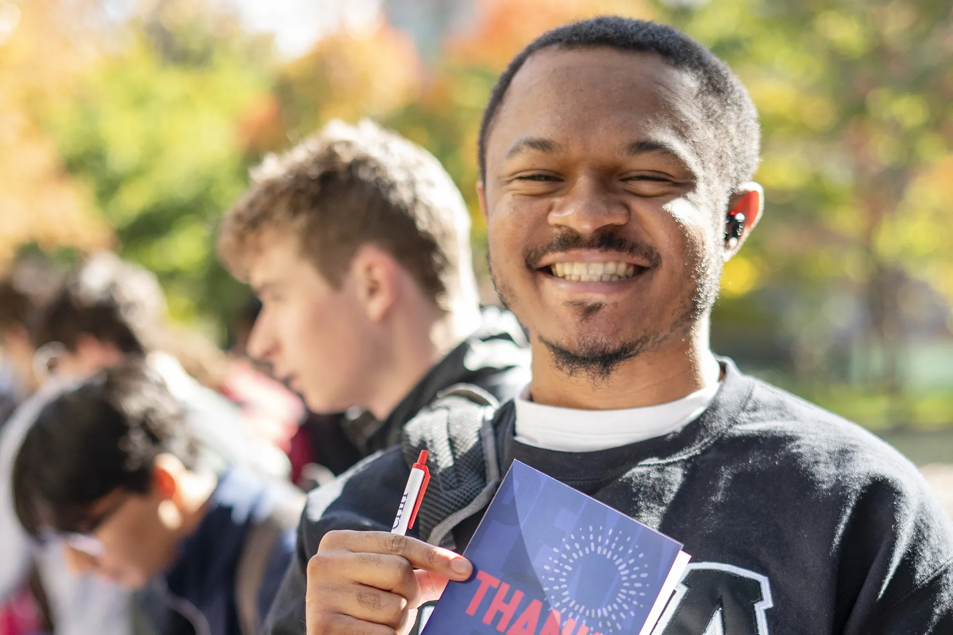 Smiling student holds up a “Thank You” card during a donor appreciation activity on Penn’s campus.